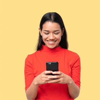 Frau auf gelbem Hintergrund lächelt und schaut auf Smartphone