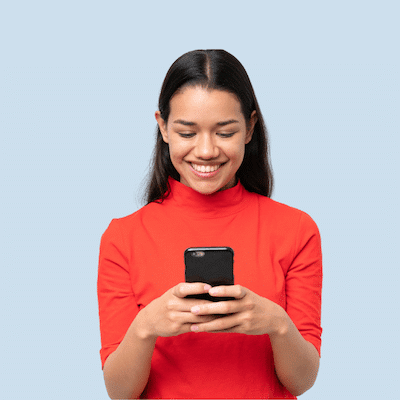 Frau auf hellblauem Hintergrund lächelt und schaut auf Smartphone