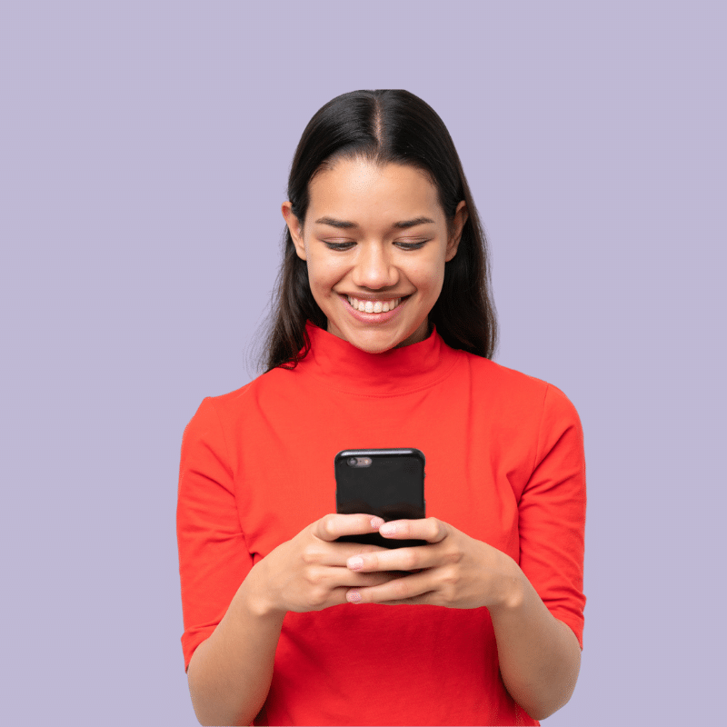 Frau auf helllila Hintergrund lächelt und schaut auf Smartphone